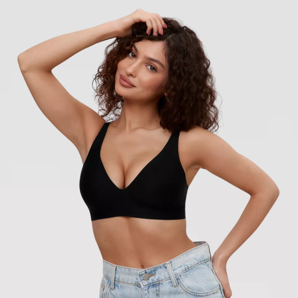Mulher com cabelo cacheado vestindo sutiã preto sem bojo e sem costura, combinando com jeans claro, transmitindo estilo, conforto e naturalidade.