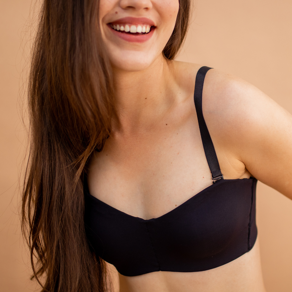Mulher sorrindo, vestindo sutiã preto com alças ajustáveis, transmitindo leveza, conforto e autoestima com lingerie básica e funcional.