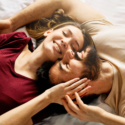 Casal deitado sorrindo, com rostos colados e expressando carinho e intimidade em um momento de afeto leve e verdadeiro.