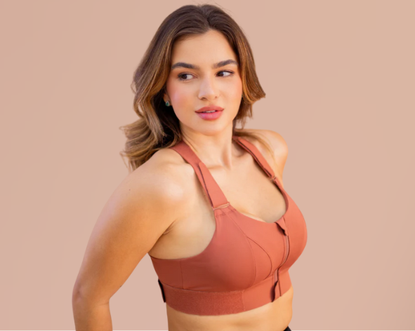 Mulher usando top fitness em tom terroso, com alças largas e design estruturado, posando com confiança em fundo neutro.