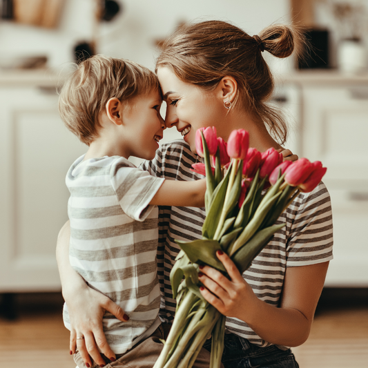 Mãe sorrindo ao lado do filho enquanto segura um buquê de flores, representando amor, carinho e celebração no Dia das Mães.
