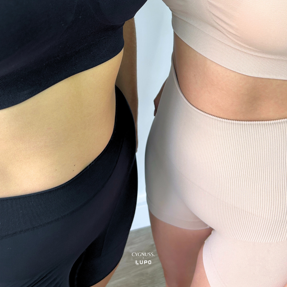 Duas mulheres vestindo Short Compression Modelador Cygnuss x Lupo, exibindo conforto e design elegante em preto e bege.