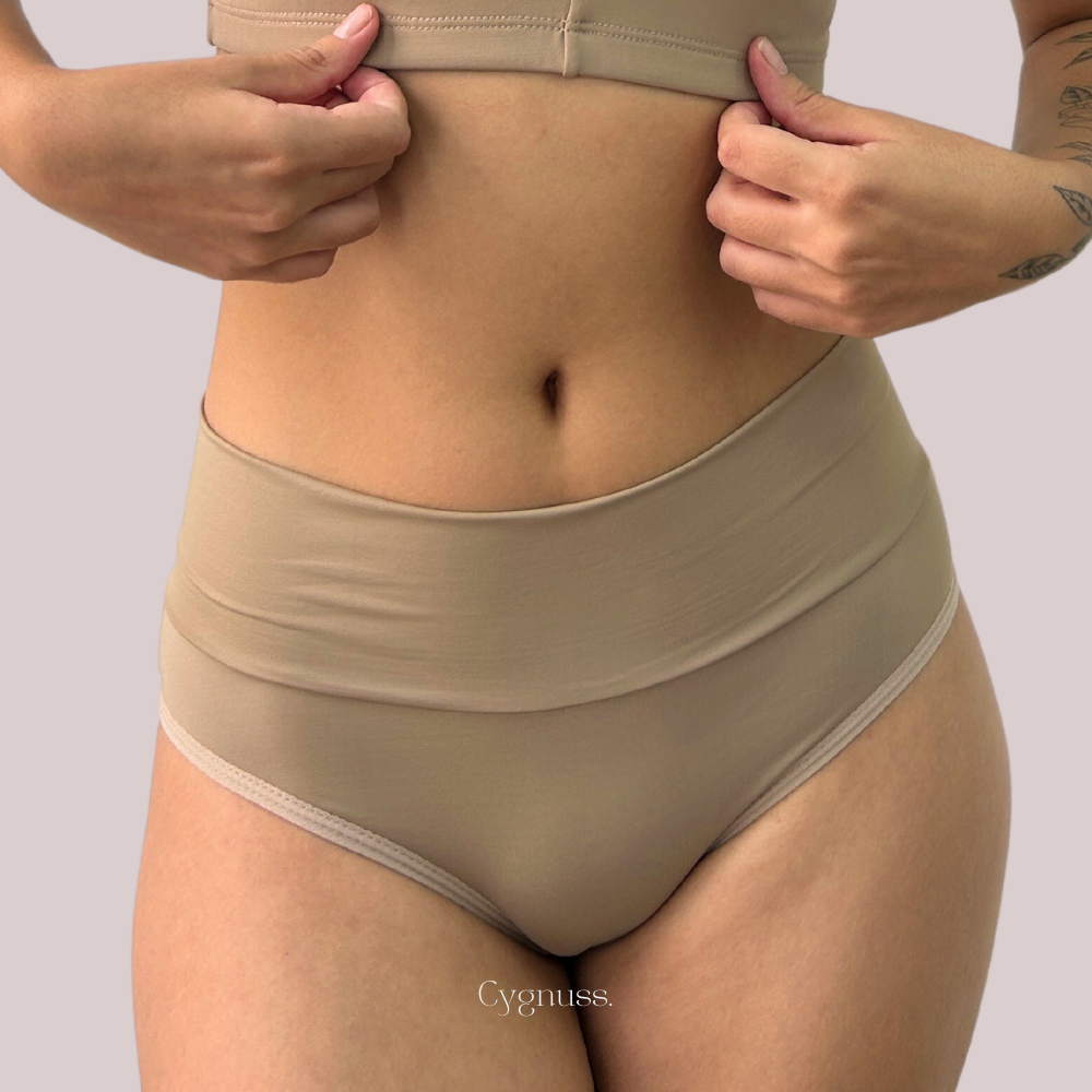 Mulher vestindo Calcinha Pandora, tanga de cintura média, exibindo conforto e estilo da Cygnuss.