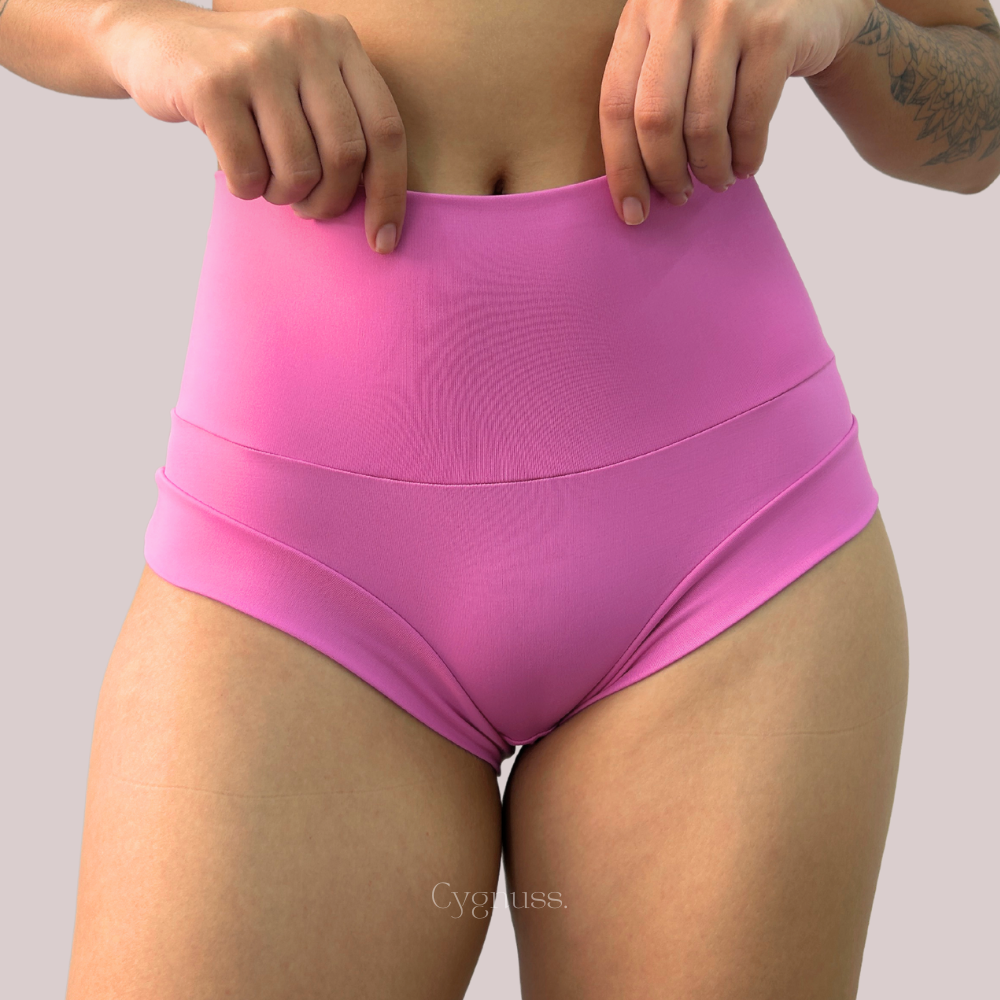 Mulher vestindo shorts rosa de cintura alta que oferecem suporte abdominal e conforto, com a marca Cygnuss.
