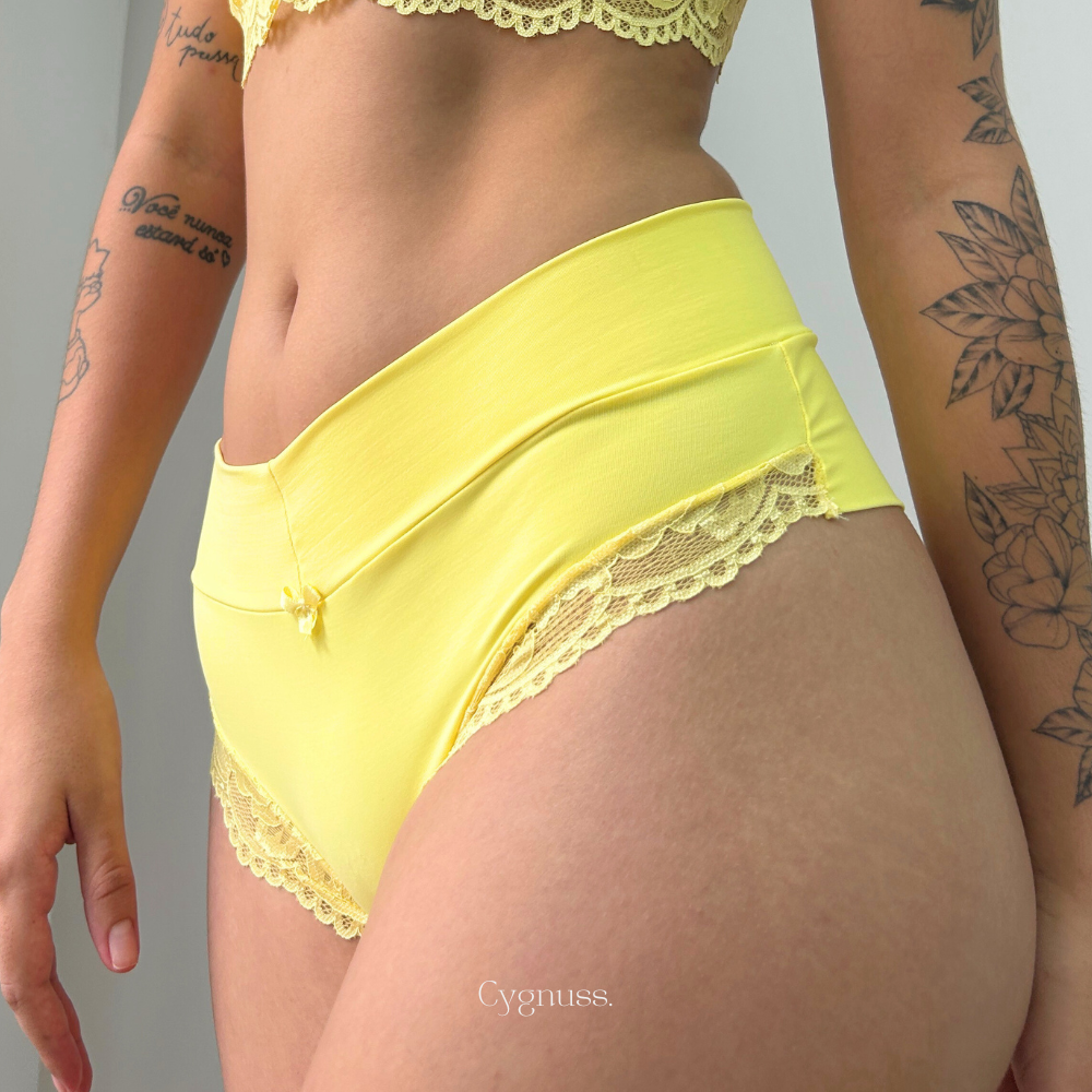 Mulher usando Calcinha Aurora com renda delicada, em amarelo brilhante, mostrando estilo e conforto da coleção de lingerie Cygnuss.