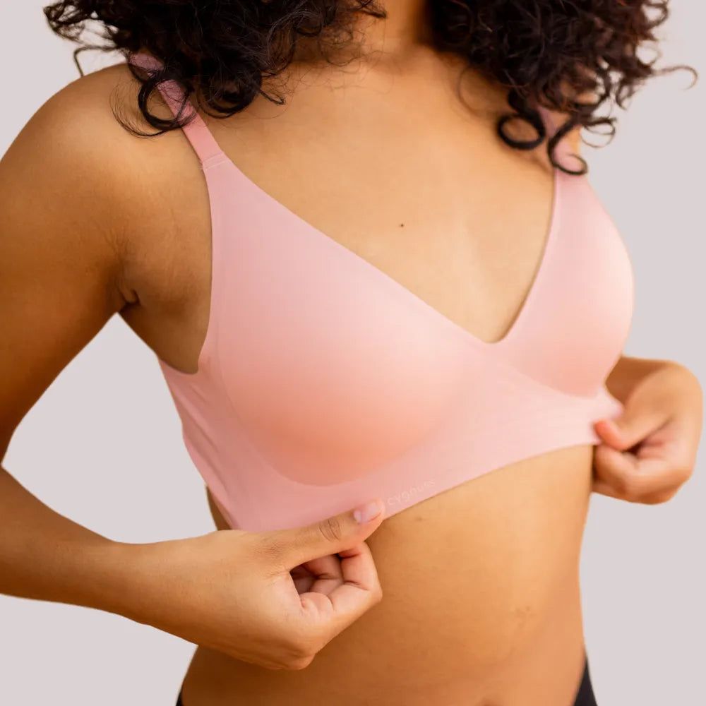 Imagem em close da modelo segurando a base do Sutiã Alça Fina Cygnuss na cor rose, destacando a elasticidade e o ajuste sem costuras.