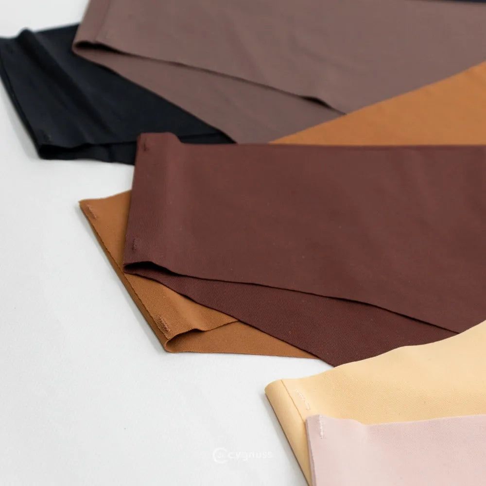 Imagem de calcinhas sem costura da Cygnuss em tons neutros, incluindo preto, marrom, caramelo e bege, dispostas sobre uma superfície clara. A variedade de cores destaca a versatilidade e sofisticação das peças.