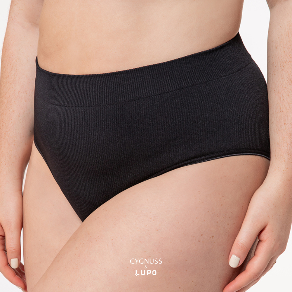 Close-up de uma mulher usando uma calcinha modeladora preta de cintura alta. O tecido canelado sem costuras proporciona ajuste confortável e efeito modelador suave, realçando a silhueta. A cintura elástica molda o corpo sem apertar. O logotipo da Cygnuss & Lupo está sobreposto na parte inferior da peça. Fundo branco minimalista.