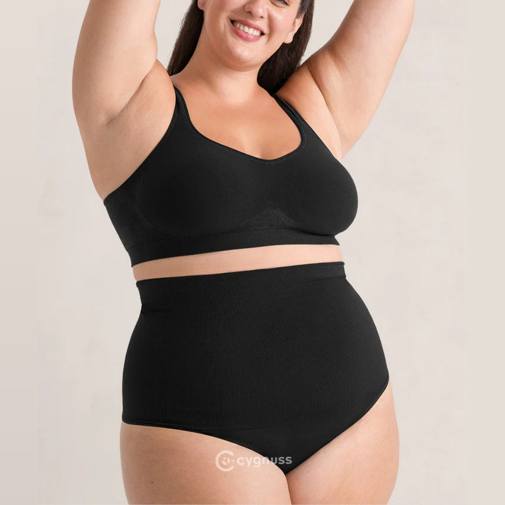 Mulher sorrindo com os braços erguidos, vestindo a Calcinha Modeladora Pêra da Cygnuss, modelo tanga na cor preta, com cintura alta canelada e top sem bojo combinando, evidenciando conforto e leve compressão.