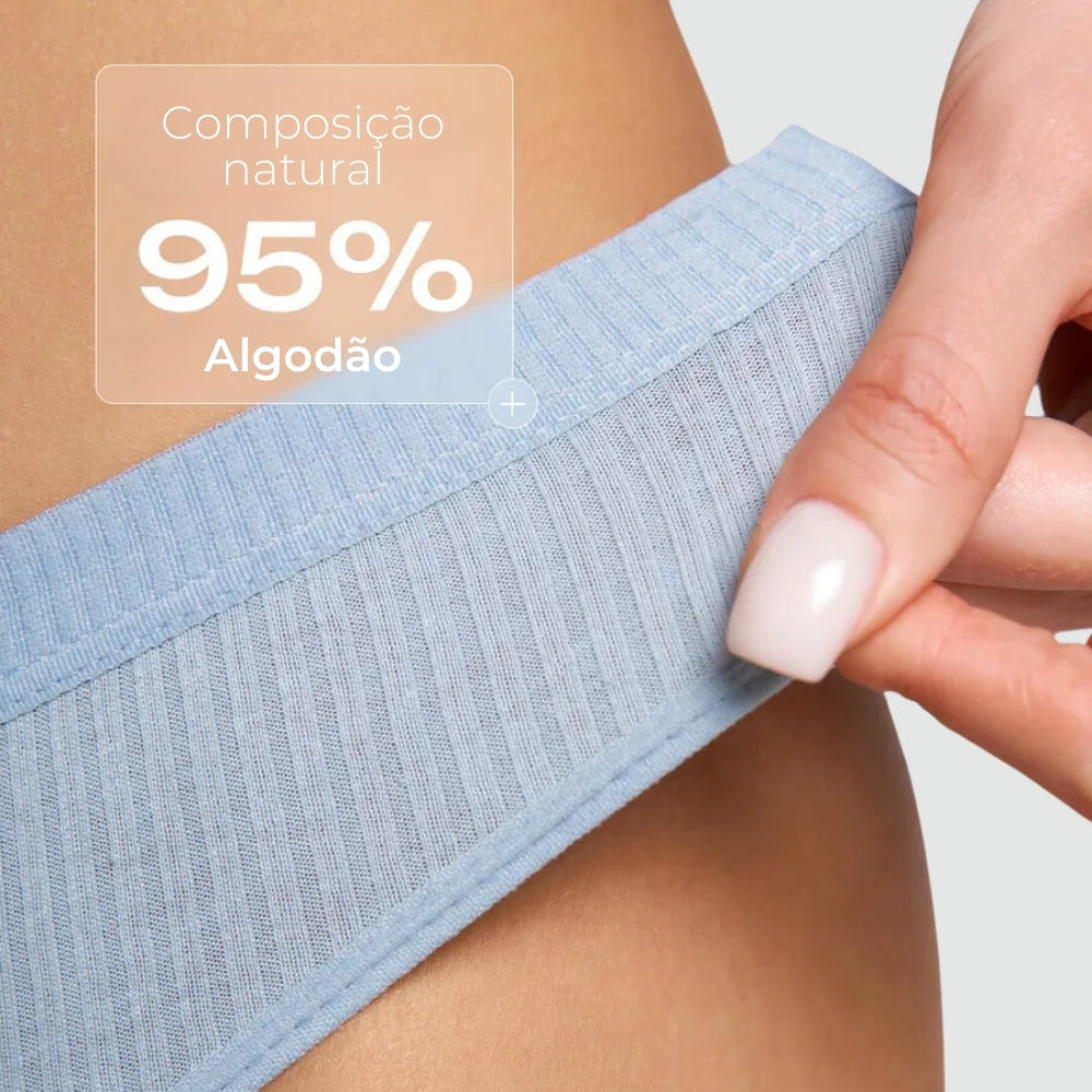 Close na lateral de uma calcinha canelada azul claro sendo levemente puxada por uma mão, destacando a elasticidade e o conforto da peça. Na imagem, aparece a frase “Composição natural 95% Algodão” em sobreposição, indicando a composição do tecido.