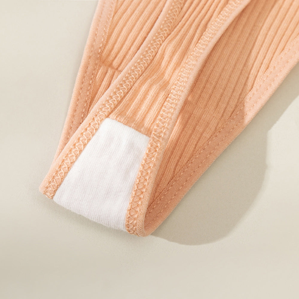 Close na região do entrepernas de uma calcinha canelada na cor terracota, destacando o forro interno em algodão branco e as costuras reforçadas. A imagem evidencia o cuidado com o conforto íntimo e a qualidade do acabamento.