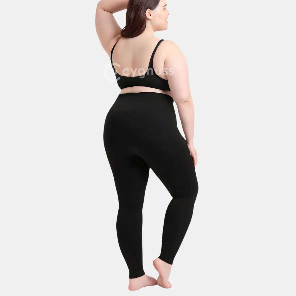 Mulher plus size de costas usando a Legging Jade Fit Modeladora de Cós Alto na cor preta, com top preto, destacando o caimento anatômico, a compressão suave e o cós alto que proporciona segurança e conforto.