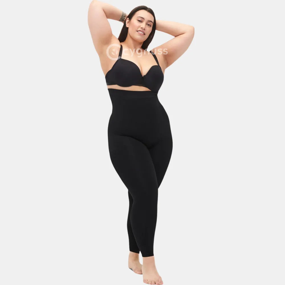 Mulher plus size usando a Legging Jade Fit Modeladora de Cós Alto na cor preta, em pose confiante com os braços erguidos, evidenciando o caimento confortável, o cós alto e o ajuste que valoriza a silhueta.