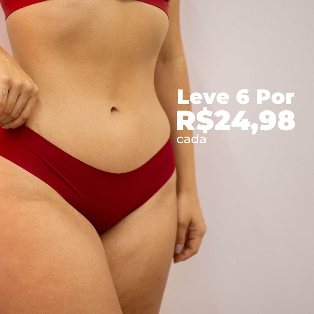 Imagem frontal da região do quadril de uma mulher usando uma calcinha fio-dental vermelha sem costura da Cygnuss, combinando com um top no mesmo tom. O texto promocional destaca a oferta de 6 unidades por R$24,98 cada.