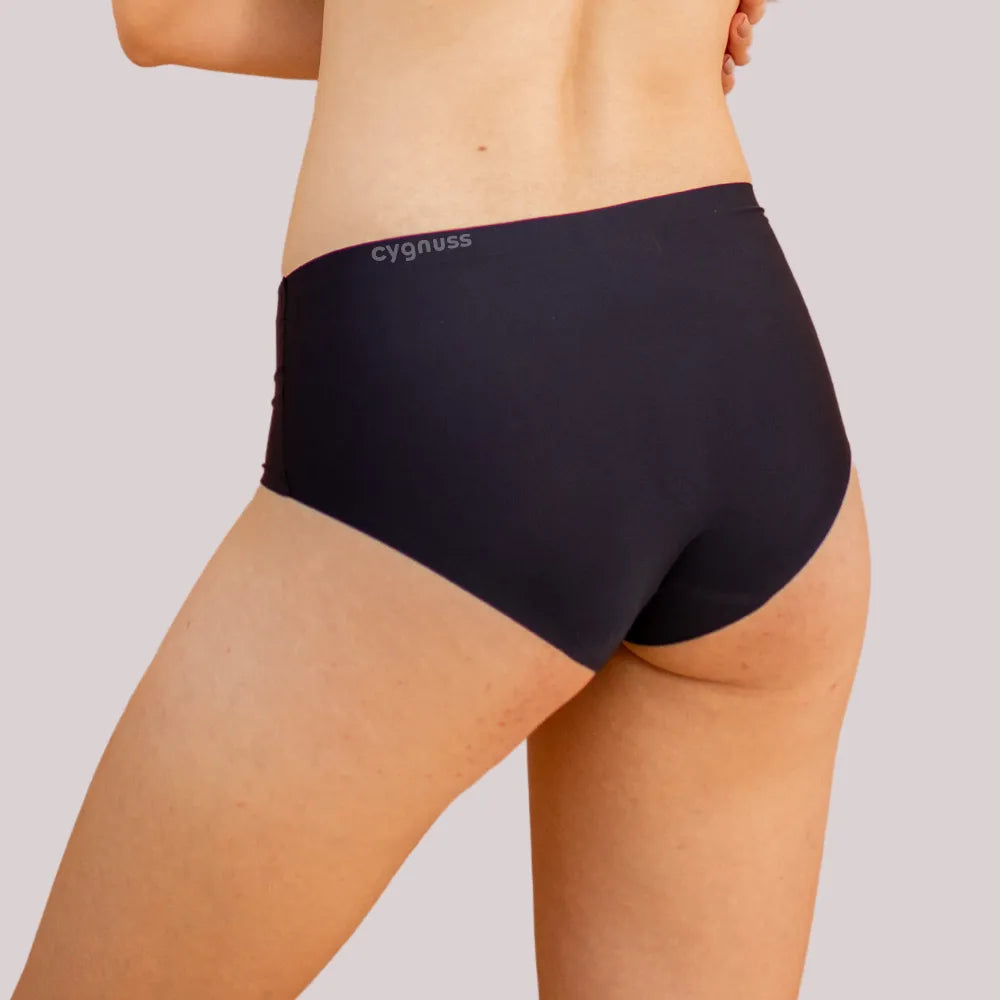Vista traseira de uma mulher usando uma calcinha preta sem costura da Cygnuss. O modelo ajusta-se perfeitamente ao corpo, oferecendo conforto e um acabamento discreto.