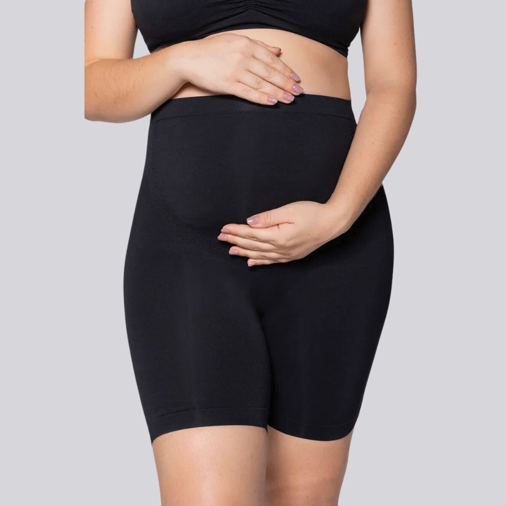 Mulher vestindo o Short Gestante Microfibra Cygnuss x Lupo na cor preta, com as mãos posicionadas sobre a barriga, destacando a modelagem confortável e o ajuste na região abdominal.
