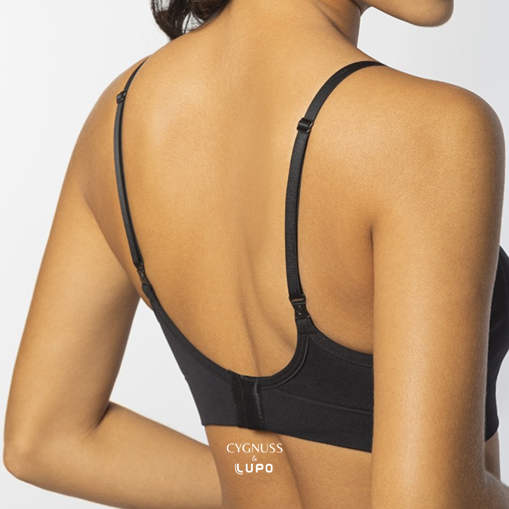 Vista traseira de uma mulher com pele morena usando um sutiã preto de alças finas ajustáveis. O design apresenta fecho traseiro e modelagem anatômica sem costuras, proporcionando conforto e sustentação. O logotipo da Cygnuss & Lupo está sobreposto na parte inferior da peça. Fundo branco minimalista.
