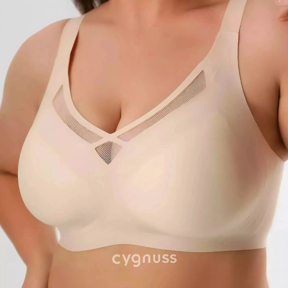 Close-up de mulher vestindo o Sutiã Dreams na cor nude, destacando o design sem costuras, com detalhes vazados em tule no decote e as alças largas para maior conforto e sustentação. O logo da Cygnuss está visível na parte inferior do sutiã.