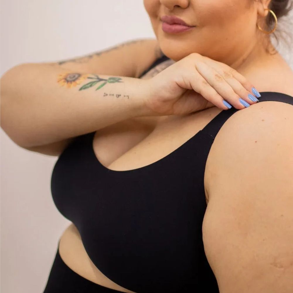Close-up de uma mulher vestindo um sutiã premium preto Cygnuss, destacando a alça larga confortável e o ajuste perfeito ao corpo.