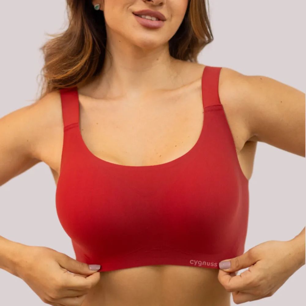 Mulher usando sutiã premium reforçado na cor vermelha, com alças largas e tecido sem costuras, ajustando a peça no corpo.
