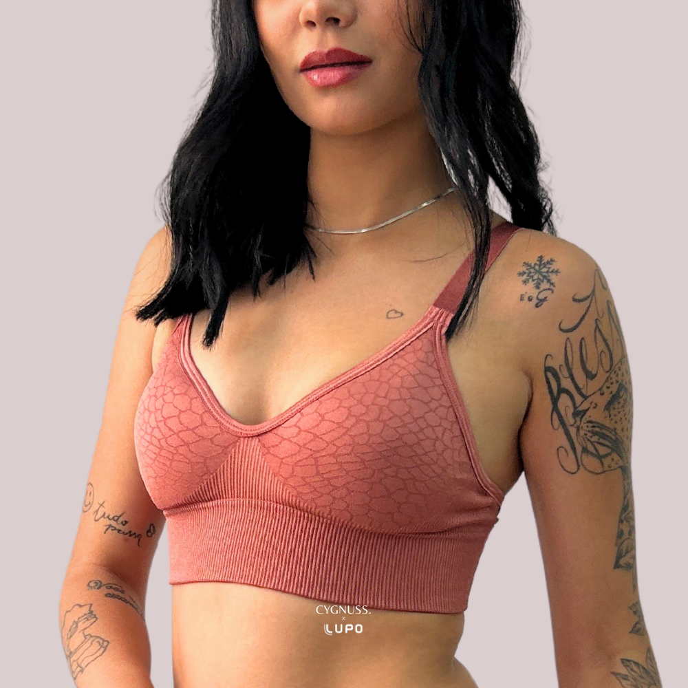 Mulher com tatuagens usando o Sutiã Trend Curves Cygnuss x Lupo na cor terracota, mostrando a textura em relevo, alças largas e o design confortável sem aro.