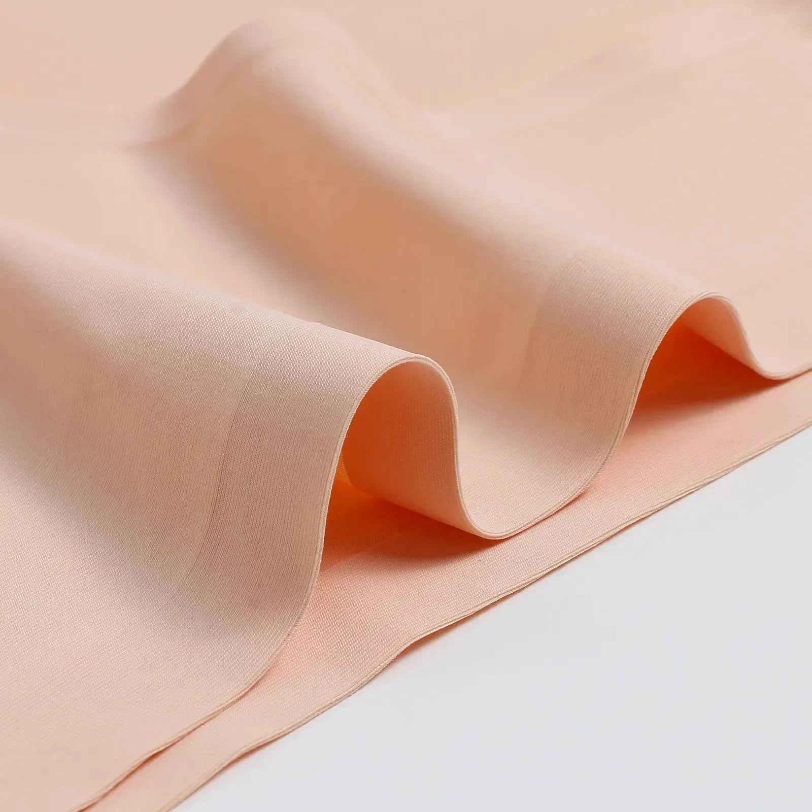 Imagem em close do tecido bege da calcinha Cygnuss, mostrando sua textura lisa e maleável. O material apresenta um acabamento suave e elástico, garantindo conforto e adaptação ao corpo.