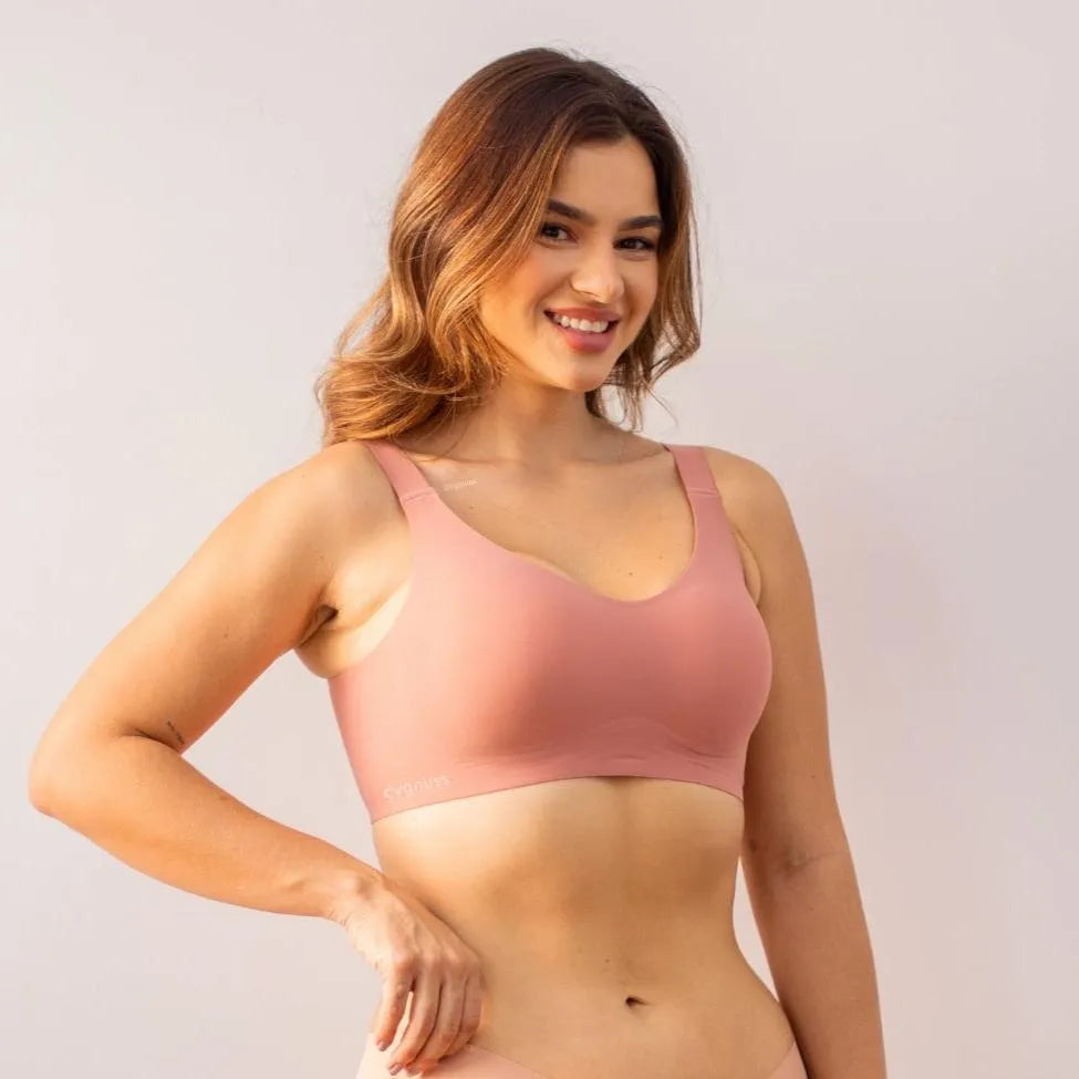 Mulher vestindo sutiã premium alça fina rosa, sem costura, oferecendo conforto e elegância, ideal para sustentação e uso invisível.