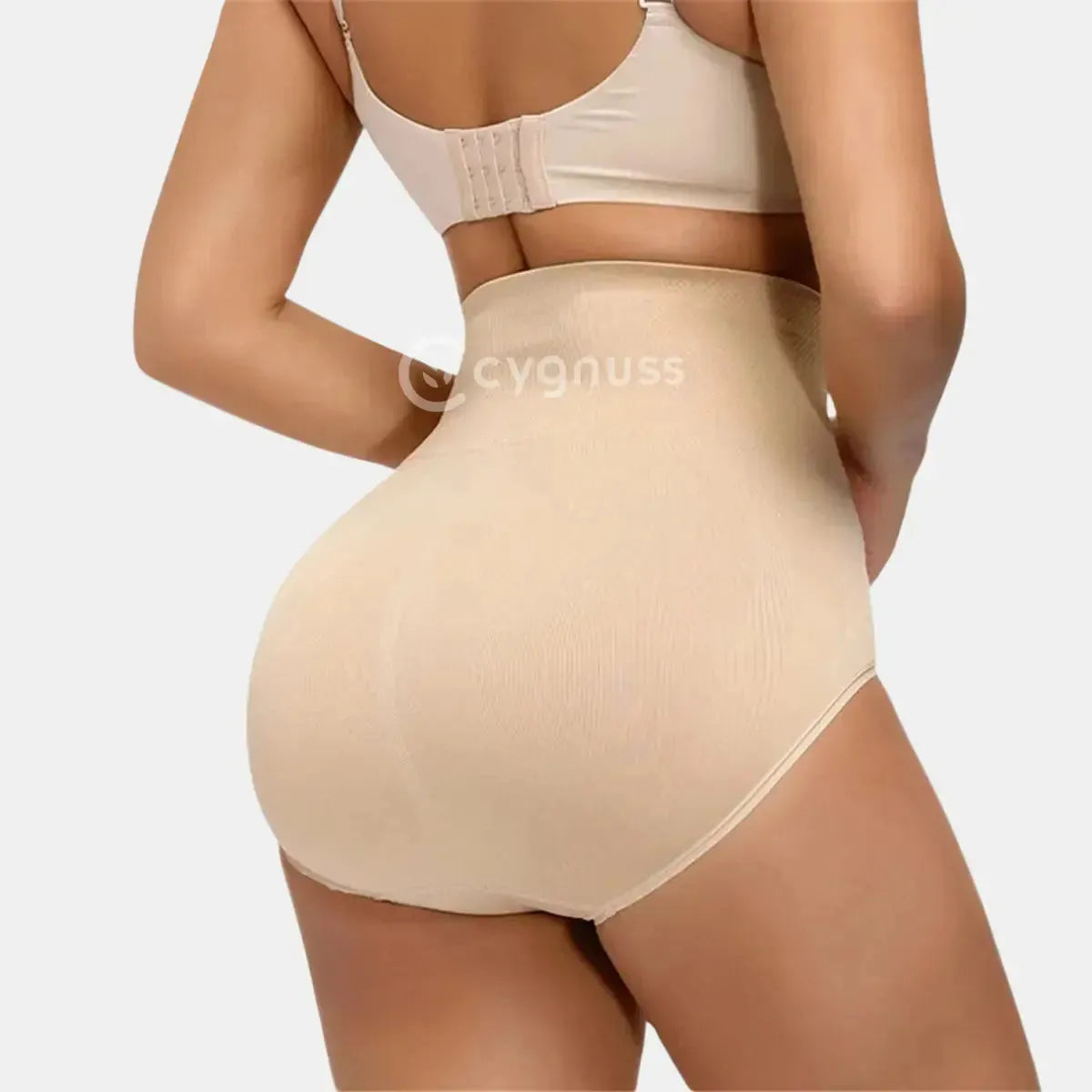 Vista traseira da Calcinha Modeladora Pêra da Cygnuss, modelo tanga na cor bege, com cintura alta e tecido modelador, destacando o efeito levanta bumbum e a valorização das curvas femininas.