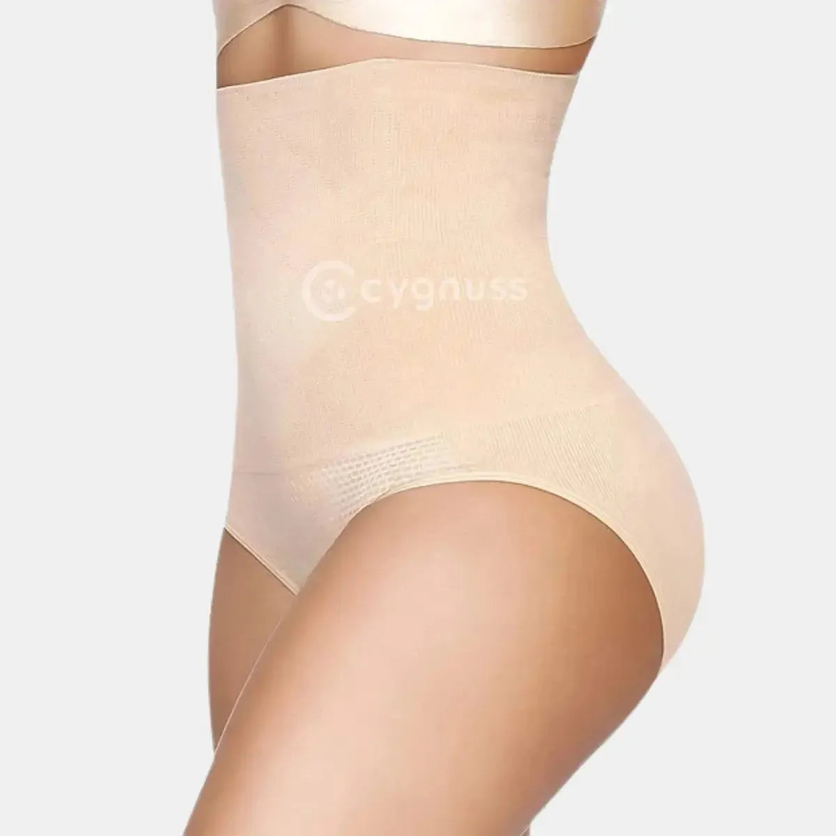 Vista lateral da Calcinha Modeladora Pêra da Cygnuss, modelo tanga na cor bege, com cintura super alta e tecido canelado, evidenciando compressão suave na região abdominal e contorno das curvas.

