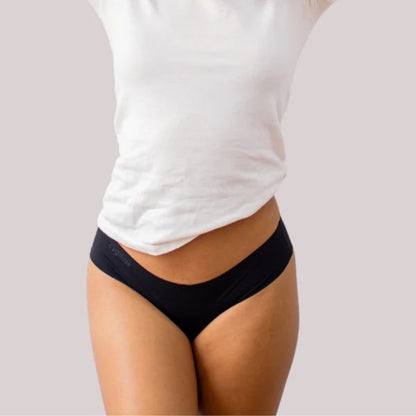Modelo vestindo calcinha preta sem costura da Cygnuss com camiseta branca, ideal para o dia a dia com conforto e discrição.