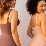 Duas mulheres sorrindo, usando bodies modeladores em cores variadas (marrom e bege), com ênfase nas alças ajustáveis e na modelagem nas costas, destacando o logo Cygnuss na parte inferior.
