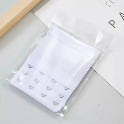 Extensor de sutia branco com tres niveis de ajuste e ganchos reforcados, embalado individualmente em plastico transparente. Ideal para adaptar o sutia com mais conforto e flexibilidade no uso diario. Fundo claro e minimalista.
