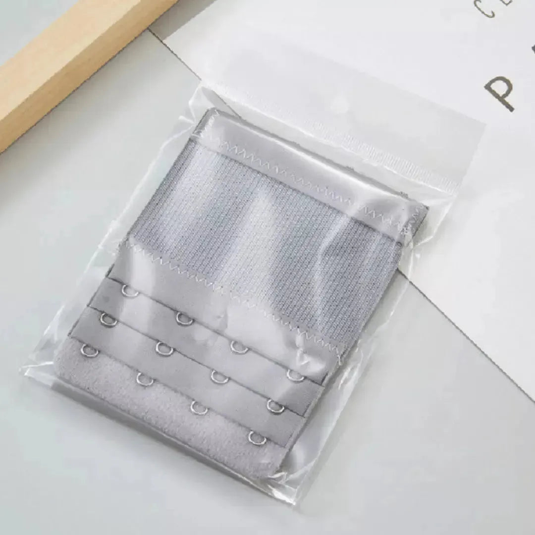 Extensor de sutia cinza com tres niveis de ajuste e ganchos reforcados, embalado individualmente em plastico transparente. Acessorio funcional para ampliar o conforto do sutia, ideal para ajustes personalizados no dia a dia.