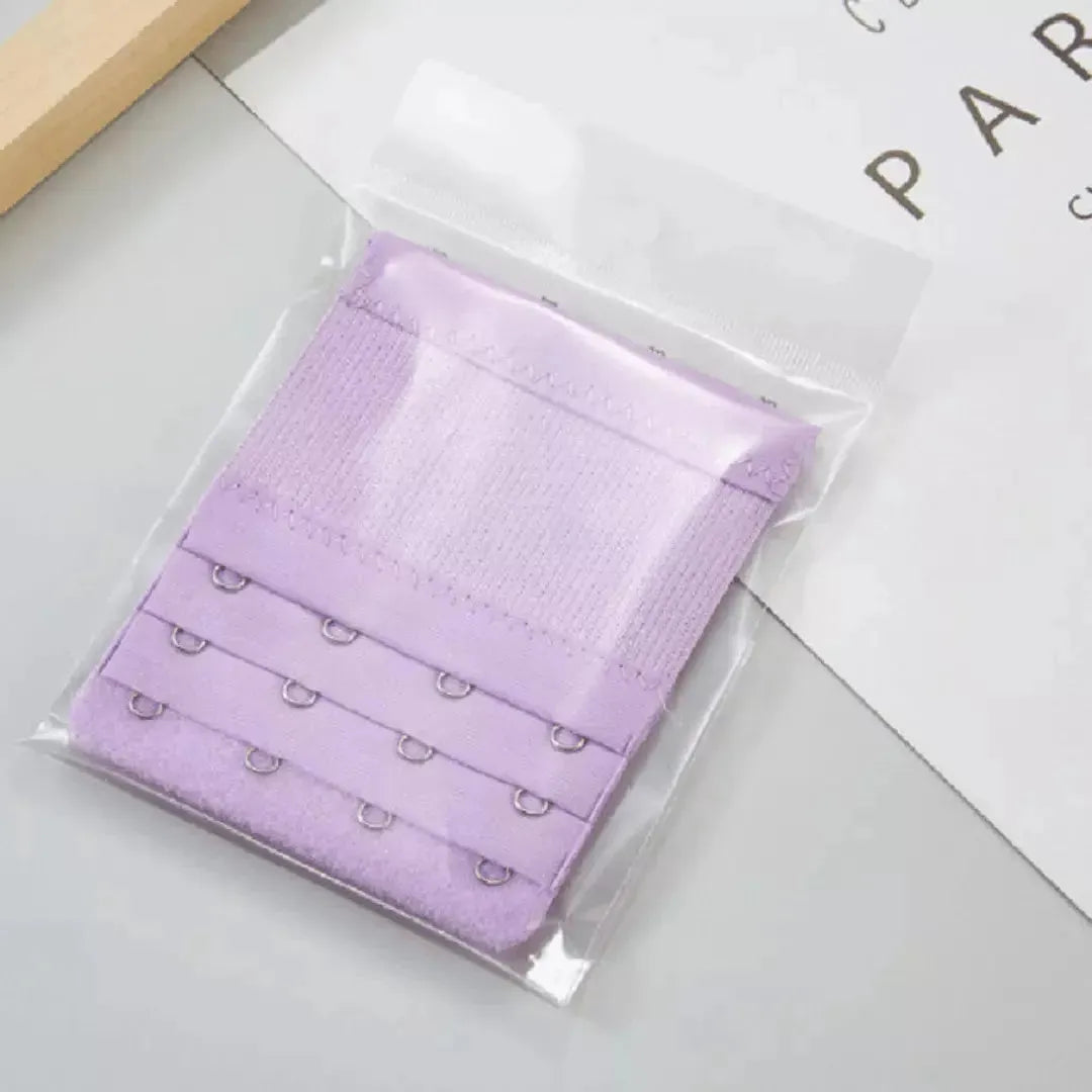 Extensor de sutia roxo com tres niveis de ajuste e ganchos reforcados, embalado individualmente em plastico transparente. Acessorio ideal para garantir mais conforto e flexibilidade no uso diario do sutia. Fundo claro e organizado.