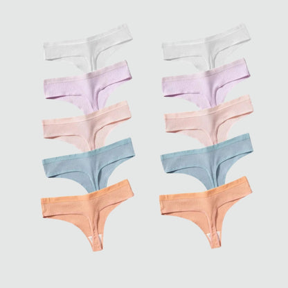 Conjunto com 10 calcinhas fio dental em tecido canelado, dispostas lado a lado em tons pastel variados: branco, lilás, rosa claro, azul bebê e terracota. As peças estão organizadas simetricamente sobre fundo cinza claro, evidenciando a variedade de cores do kit.