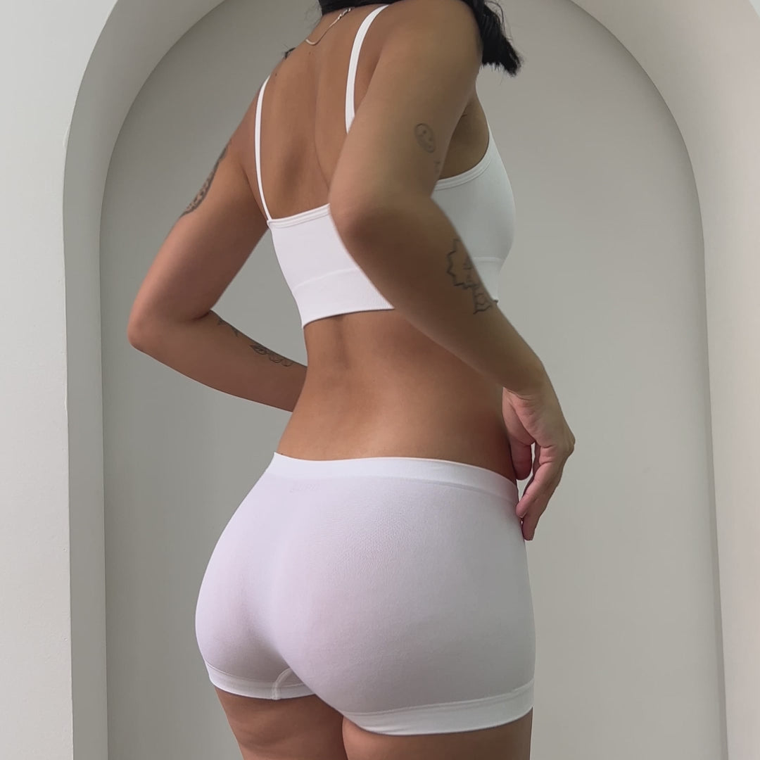 Mulher usando Top Power Básico Sem Costura Cygnuss x Lupo em branco para sustentação e conforto, com tecido respirável.