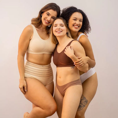 Três mulheres sorridentes vestindo o Sutiã Daily Original em diferentes cores: bege, marrom e branco. A peça sem costura proporciona conforto e ajuste perfeito para diferentes tipos de corpos.