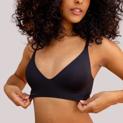 Mulher vestindo sutiã preto, sem aro e sem costura, com alças finas ajustáveis; elegante e confortável ajuste invisível.