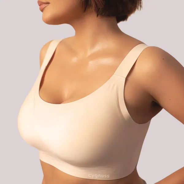 Mulher vestindo sutiã Cygnuss bege com modelagem lisa e alças largas, sem costuras aparentes, oferecendo conforto, sustentação e visual minimalista