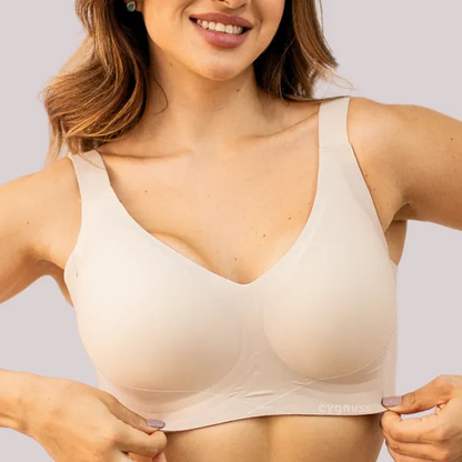 Mulher vestindo sutiã modelador bege da marca Cygnuss, com tecido liso, alças largas e estrutura sem costuras visíveis, proporcionando conforto e sustentação.