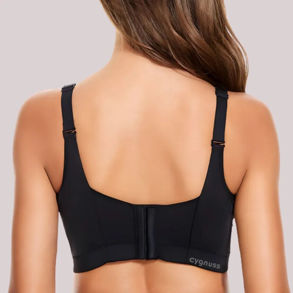 Mulher vista de costas vestindo o Sutiã ElevaTop – Super Sustentação push up da Cygnuss na cor preta. A imagem mostra as alças largas reguláveis e o fecho traseiro reforçado com múltiplos colchetes. O logo "cygnuss" aparece na lateral inferior da peça.