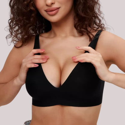 Mulher vestindo o Sutiã FIT da Cygnuss na cor preta, com alças finas e bojo removível. A imagem frontal destaca o decote profundo em V, o ajuste perfeito e o toque moderno e minimalista da peça, ideal para valorizar o busto com leveza e conforto.