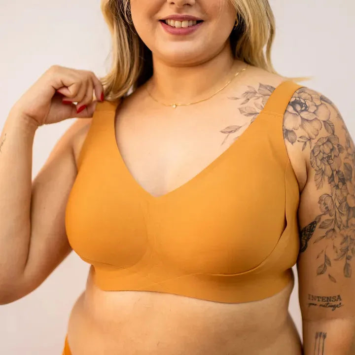Mulher plus size usando sutiã modelador Cygnuss na cor mostarda, com alças largas, tecido liso e design anatômico, proporcionando sustentação e conforto com elegância.