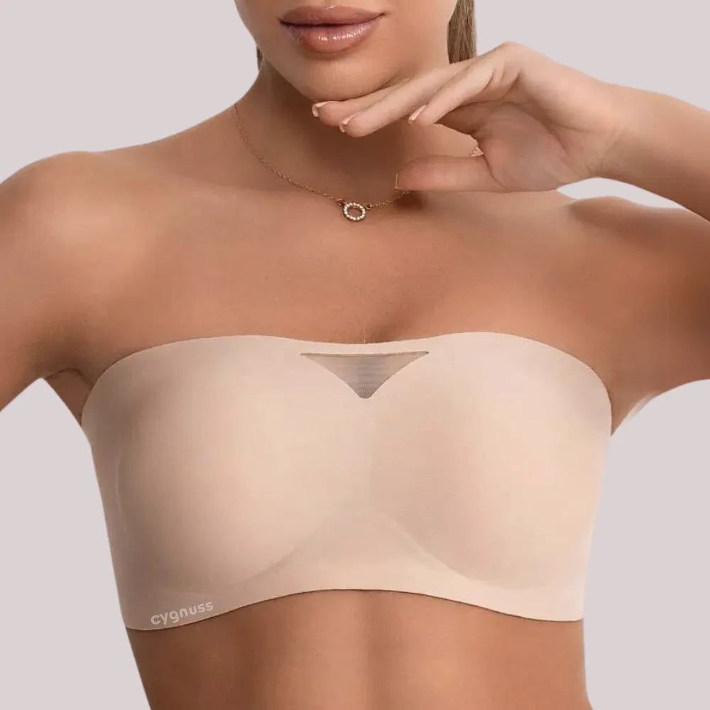 Close do sutiã tomara que caia bege da Cygnuss com detalhe em tule no centro e acabamento sem costura, usado por modelo com colar delicado.