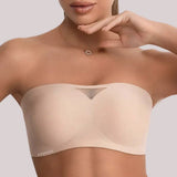 Close do sutiã tomara que caia bege da Cygnuss com detalhe em tule no centro e acabamento sem costura, usado por modelo com colar delicado.