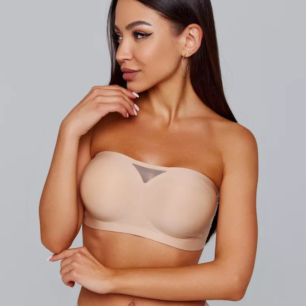 Modelo usando sutiã tomara que caia bege da Cygnuss com detalhe em tule no centro, olhando para o lado com pose elegante e acabamento sem costura.